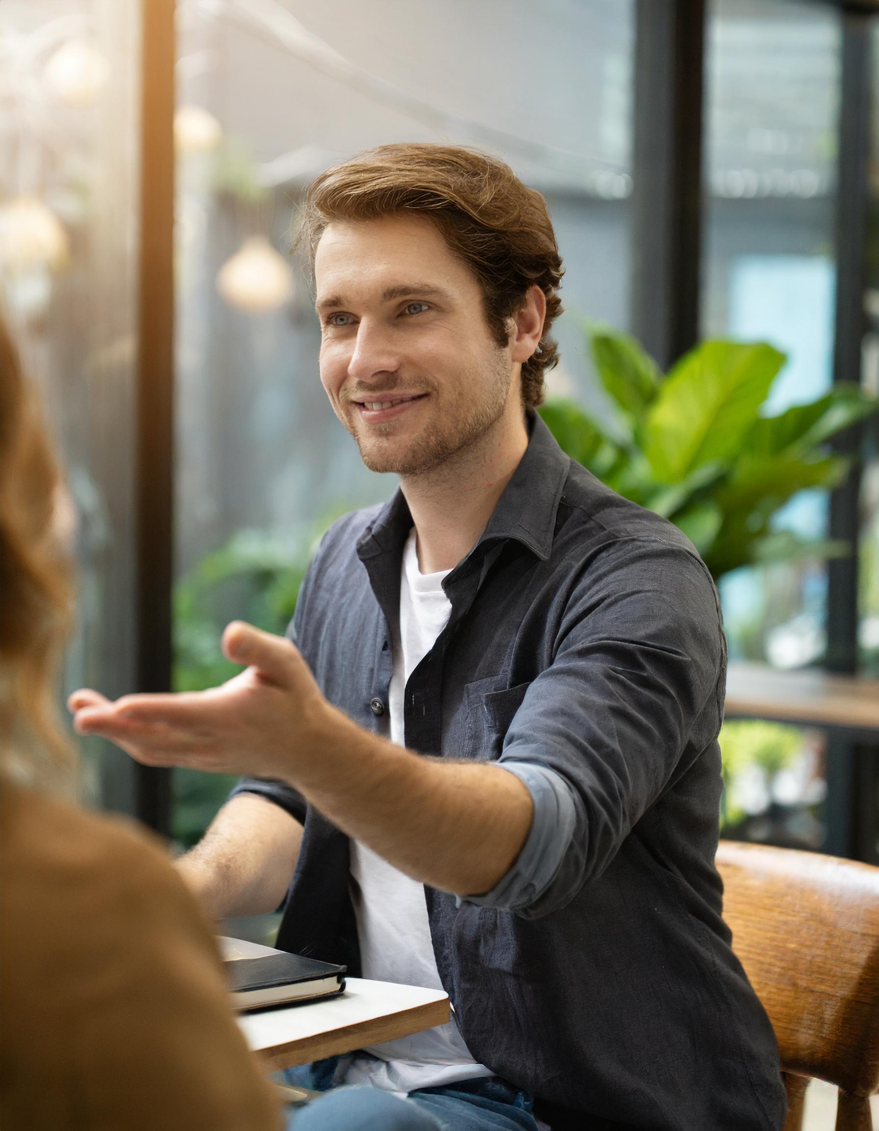 Mann im Gespräch mit Kunden, entspannt und lächelnd, in einem gemütlichen Büro