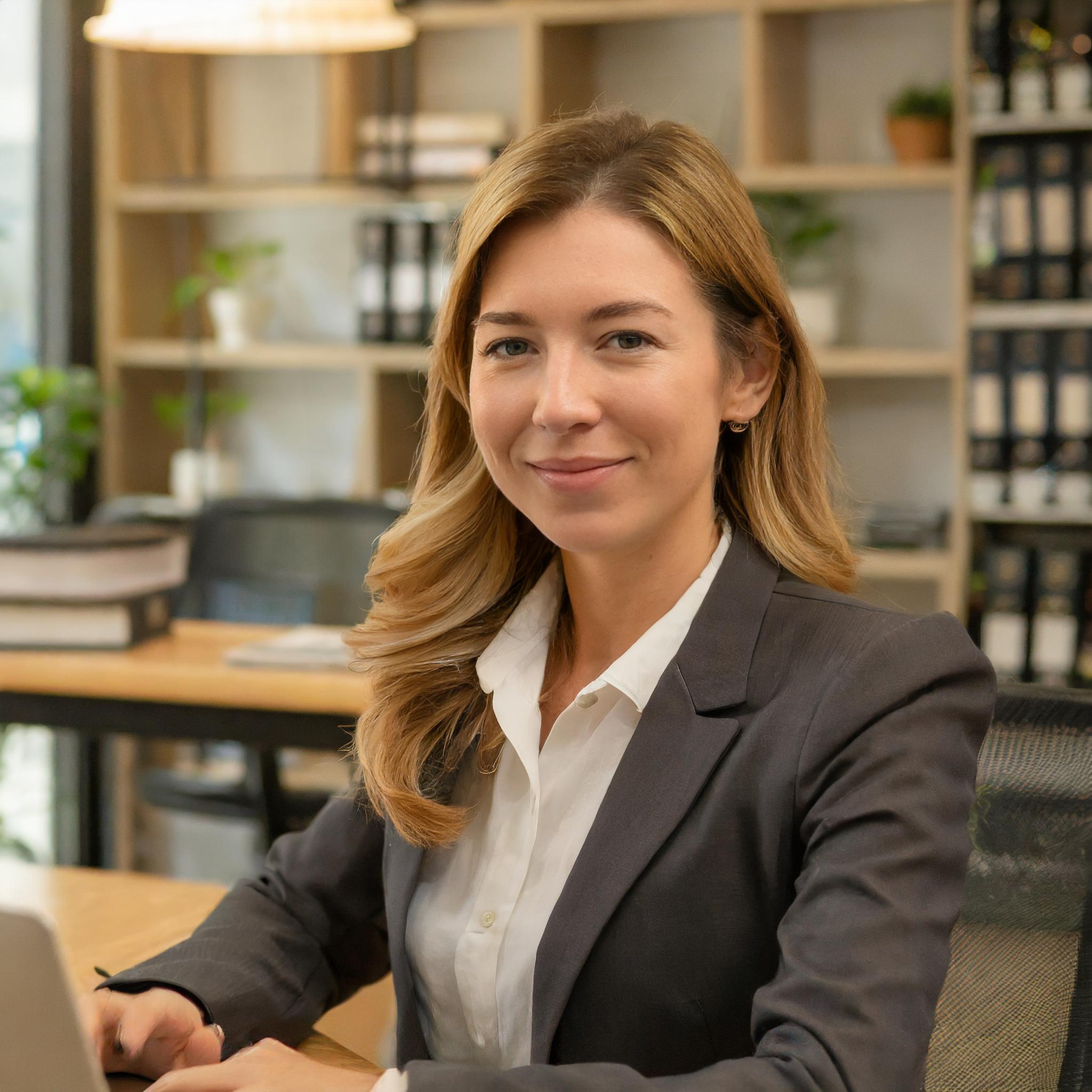 Frau, die lächelnd am Laptop arbeitet, mit Marketingmaterialien und bunten Grafiken umgeben